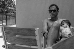 אב מחזיק תינוק על ברכיו ברגע שקט של קרבה, צילום משפחה דוקומנטרי מאת טל גולדשטיין