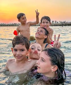 משפחה משתעשעת במים בשעת שקיעה צילום משפחתי טבעי ומלא חיים מאת טל גולדשטיין